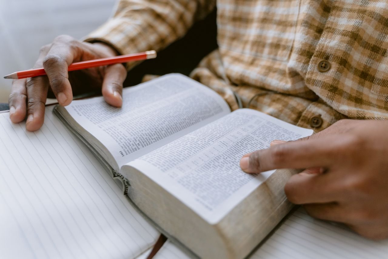 The Art of Drawing Readers In: Your attractive post title goes here Hands holding an open Bible while taking notes with a pencil.