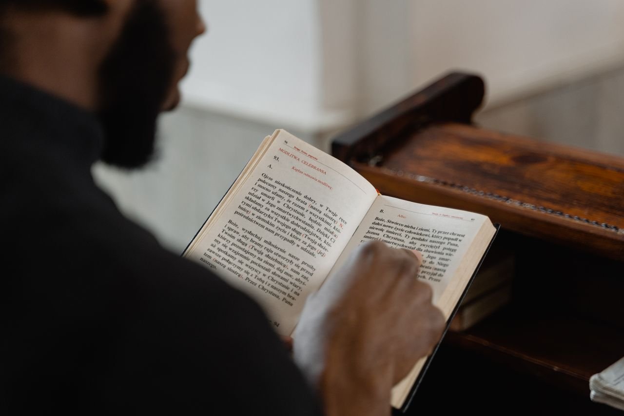 Crafting Captivating Headlines: Your awesome post title goes here A man reading a religious book inside a church, focusing on a spiritual moment.